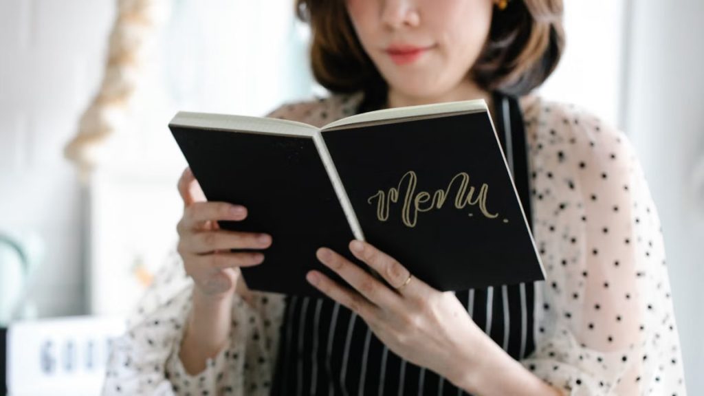 Close-up of a woman holding and reading a menu indoors.