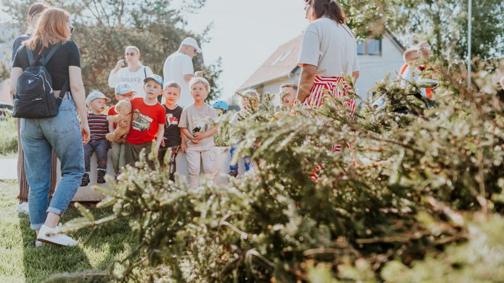Children and adults participating in an outdoor educational activity surrounded by nature.